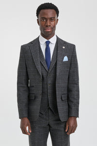 Man wearing a gray checkered suit with a blue tie and pocket square on a white background