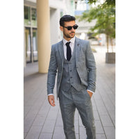 Man wearing a gray suit and sunglasses on a city street